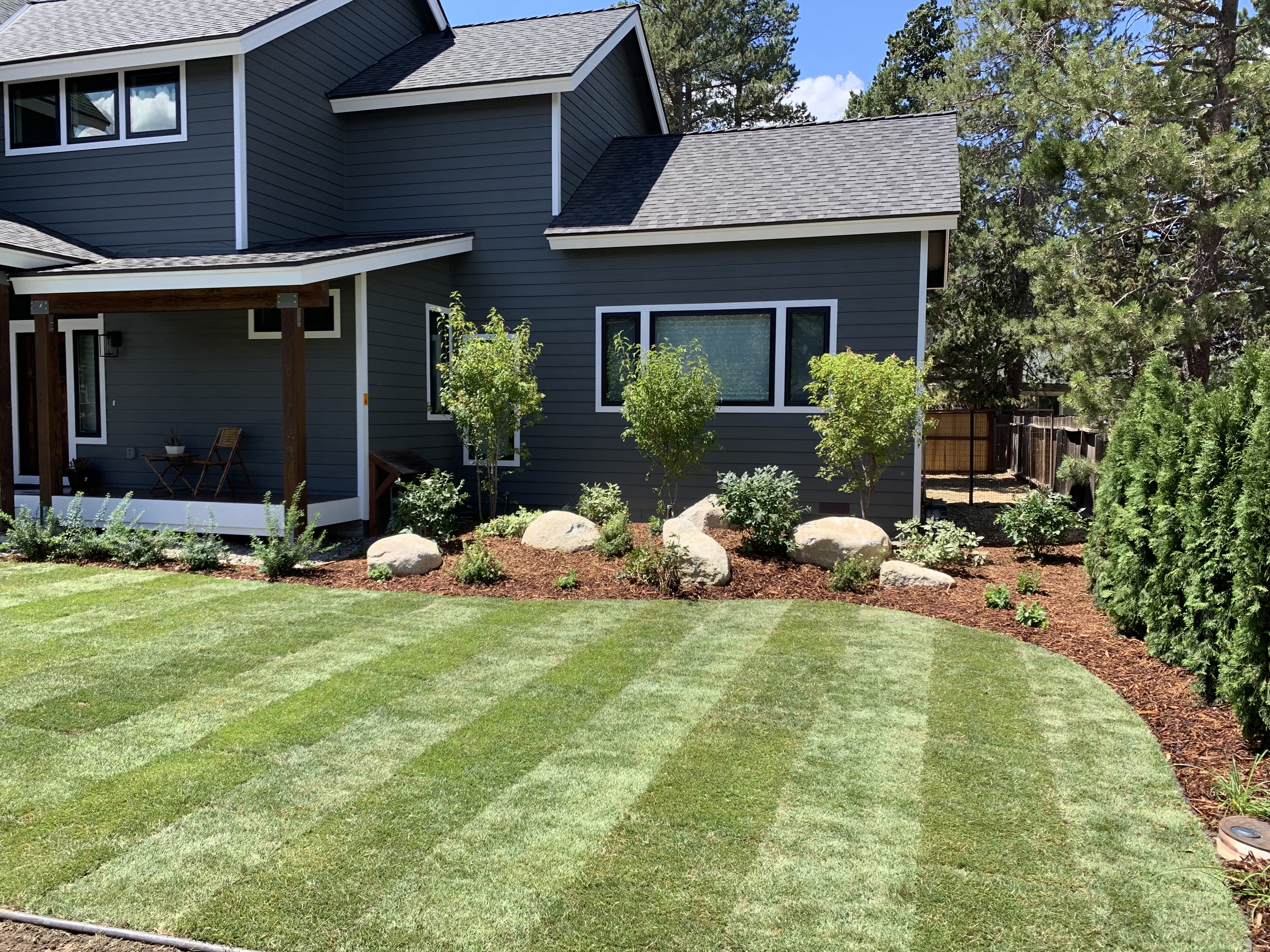 Freshly mowed Tahoe lawn with clean mowing lines, mulch beds, boulders, and young trees